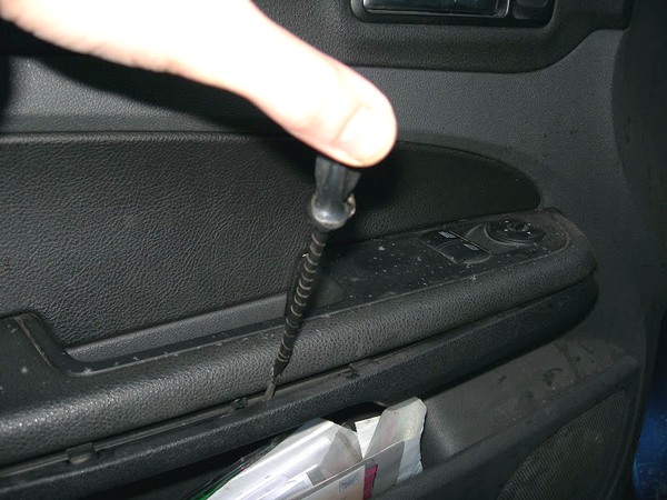 Отверткой поддеваем нижнюю накладку подлокотника Ford Focus 2